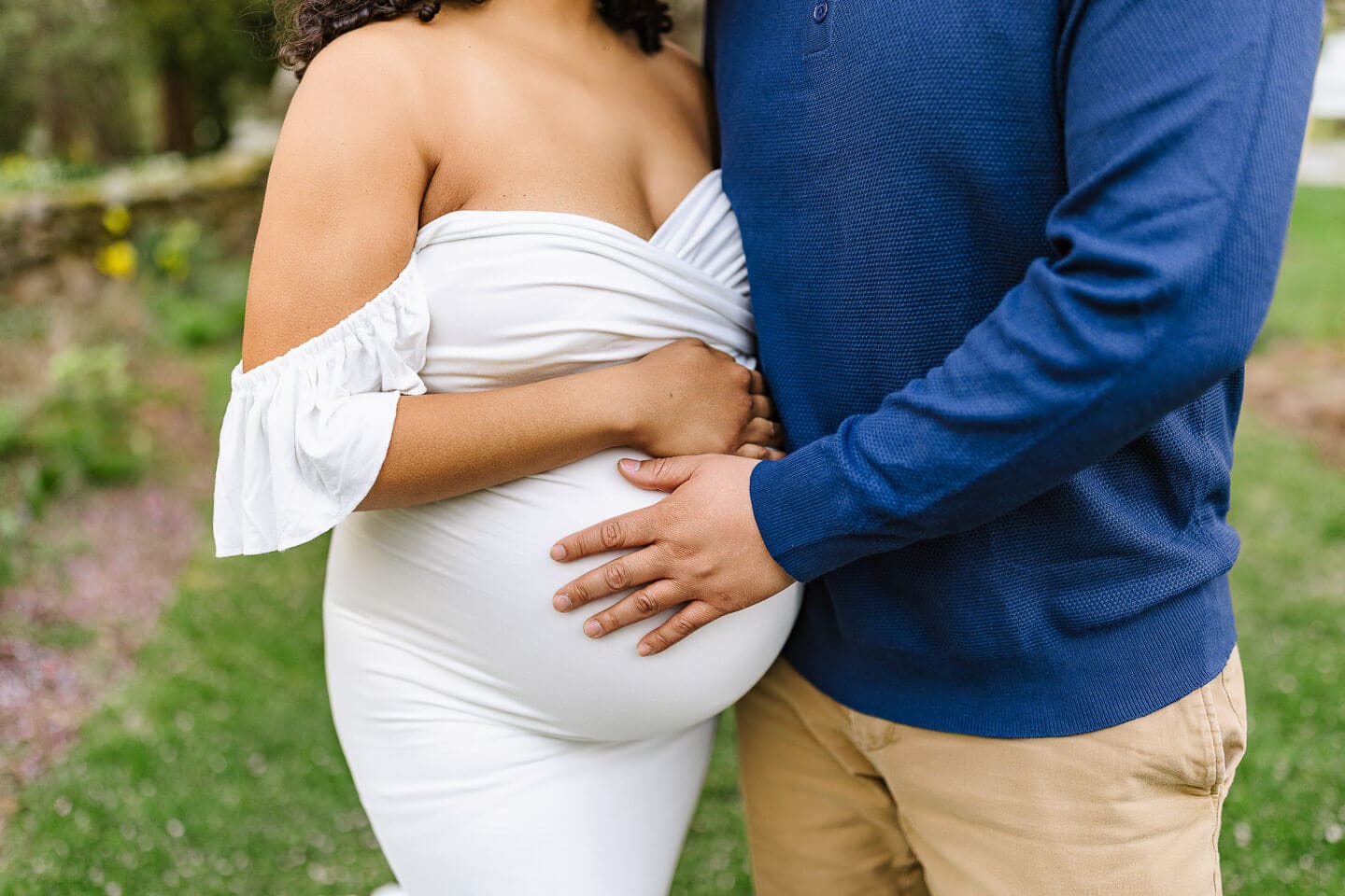 Detail image of expecting parents' hands on a baby bump during a maternity photography session in Bristol, Rhode Island.
